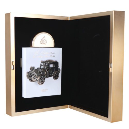 Open box view of La Collection D'antiquités 1886 Eau De Parfum by Lattafa, revealing a white bottle with an antique car design inside a gold case.