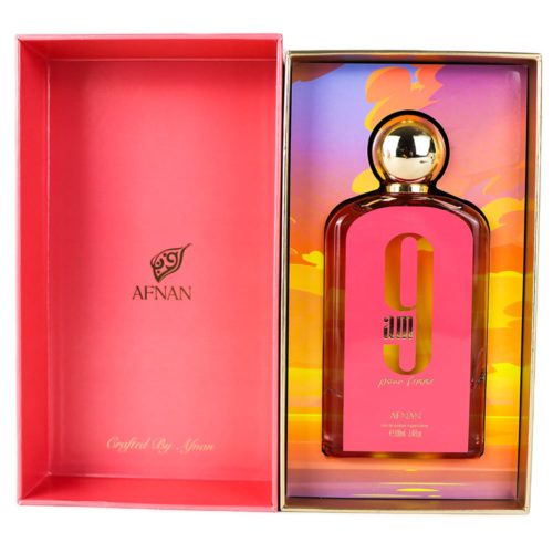 An open perfume box revealing the "9 AM pour femme" bottle inside. The inner packaging has a colorful gradient background with hues of orange, yellow, and purple, complementing the golden cap of the bottle.